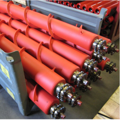 Multiple red-coated spiral rollers stacked in an industrial rack, ready for shipment to bulk material handling facilities