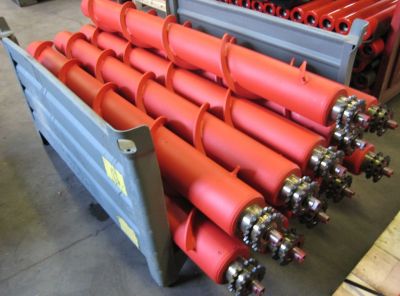 Industrial sprocket-driven conveyor rollers featuring a welded steel spiral cleaning profile and double chain sprockets stacked in a transport crate