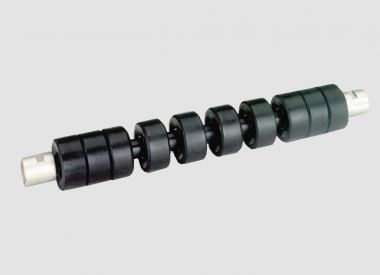 Rigid return idler with rubber rings for belt cleaning and smooth support of the empty conveyor belt return side