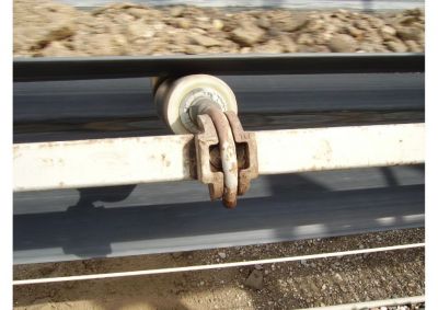 Close-up view of the spring-loaded suspension for garland conveyor idlers, enabling dynamic trough angle adjustment
