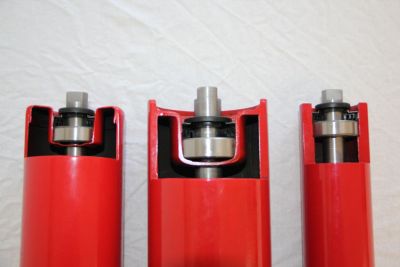 Top view: Cross-section comparison of red conveyor idlers showcasing standard design, heavy-duty housing (SLT), and machined counter-bored bearing seat (HLR)