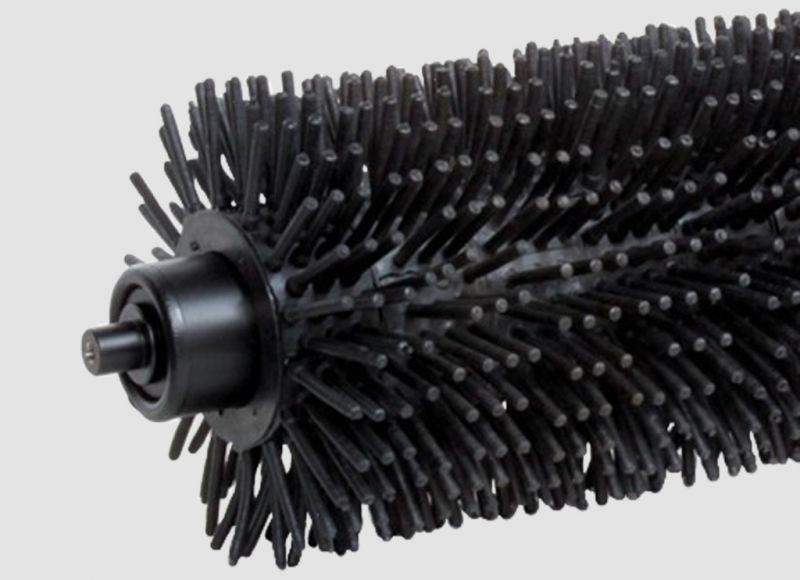 Brush roller with dense black bristles designed for continuous belt cleaning and debris removal on conveyor systems