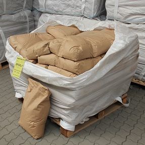 Effizienter Schlackenbinder SPORLIT für den Eisen- und Stahlguss mit Produktetikett und einzelnem Papiersack vor einem Big Bag