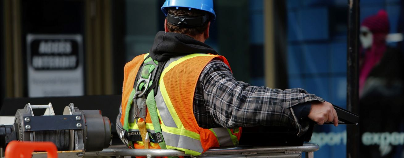 Worker wearing personal protective equipment (PPE) including a hard hat and safety vest in an industrial setting