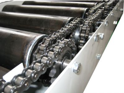 Sprocket-driven conveyor rollers in action, transferring heavy pallets on an automated roller conveyor system inside a warehouse