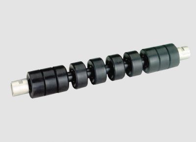 Rigid return idler with rubber rings for belt cleaning and smooth support of the empty conveyor belt return side